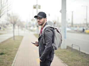 man wearing black leather jacket holding smartphone
