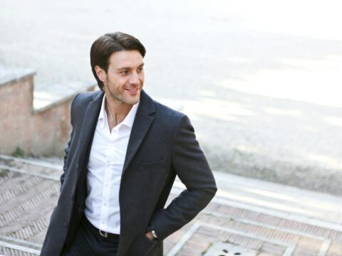 man in white dress shirt and black blazer standing outside building